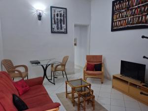 a living room with a red couch and a table at Appartement Keur Diam Saly in Saly Portudal