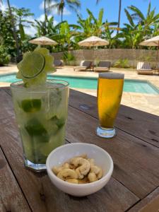 a wooden table with a bowl of nuts and a drink and a glass of juice at Pousada Vila Icaraí in Icaraí