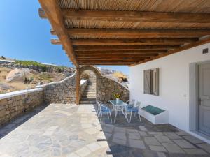 a patio with a table and chairs under a wooden roof at Parfait Villa, Mykonos in Agios Ioannis Mykonos