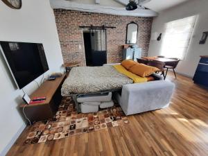 a bedroom with a bed and a couch and a brick wall at La Grange de Lilou in Aiffres