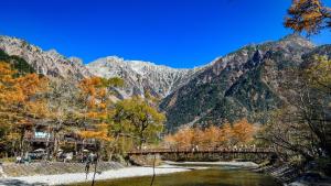 a bridge over a river with mountains in the background at Hirayukan in Takayama