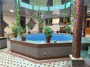 a large swimming pool with potted plants in a building at Kifoyat Hotel in Samarkand