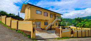 a yellow house with a fence in front of it at Lyn Tropical Getaway in Port-of-Spain