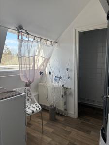 ein Zimmer mit einem weißen Stuhl und einem Fenster in der Unterkunft Le Bachelin in Saint-Omer
