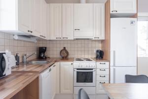 a kitchen with white cabinets and white appliances at Villa Magnolia 1 Himos in Jämsä