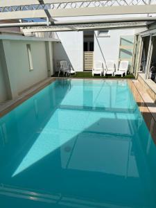a swimming pool with blue water and white chairs at Camere a Sud in Alliste