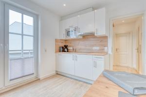 a kitchen with white cabinets and a large window at Schmidt-einander W10 in Norderney