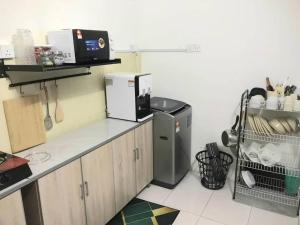 a kitchen with a counter with a microwave and a refrigerator at Abadi Homestay Ipoh in Ipoh