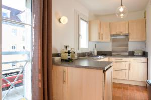 a kitchen with wooden cabinets and a large window at Chez Leela in Poissy