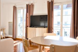a living room with a table and a tv at Chez Leela in Poissy
