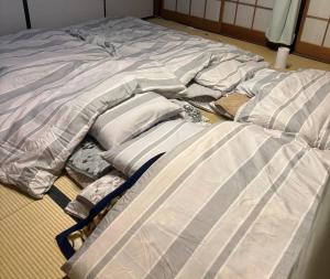 an unmade bed with sheets and pillows on the floor at 杜の酵素808 in Takaharu