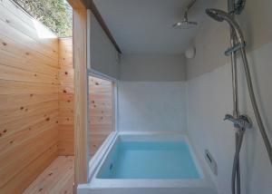 a tub in a bathroom with a wooden wall at OKANiWA 丘庭 in Nagiso