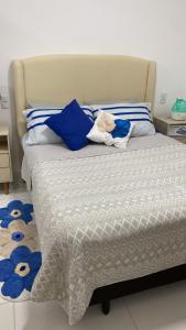 a bed with blue and white sheets and blue pillows at Apartamento em Condomínio Clube Completo com Piscina in Vitória da Conquista