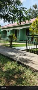 a green building with a fence in front of it at Pross Residence in Masindi +21 photos