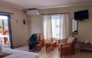 a bedroom with a bed and two chairs and a television at Karoo-Koppie in Colesberg