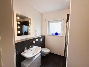 a bathroom with a sink and a toilet and a mirror at Ferienwohnung RuheOase in Steinheim +18 photos