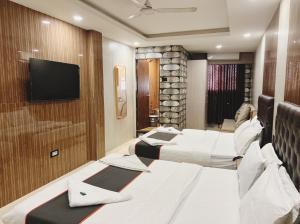 a hotel room with three beds and a flat screen tv at U LIFE HOTEL in Mumbai
