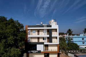 a tall white building with trees in front of it at hotel nemi residency jagdalpur in Jagdalpur
