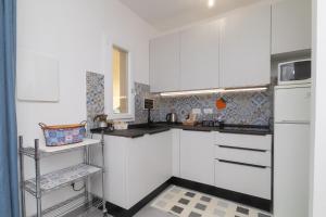 a white kitchen with white cabinets and a microwave at Casa Brezza Marina in Punta Marina +16 photos