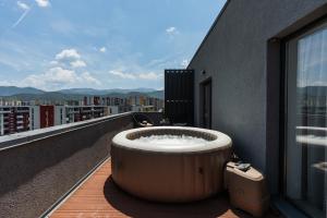 a bath tub on the balcony of a building at Skylark - Singapore Penthouse with Jacuzzi & Panoramic View in Braşov