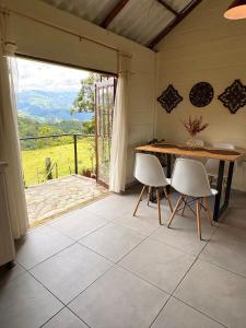 a dining room with a table and chairs and a large window at La Morada Quindio cabaña campestre in Boquía