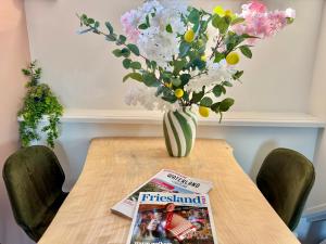 a table with a vase of flowers and a magazine at Boutique Hotel Joure - centrum & haven in Joure