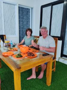 a man and a woman sitting at a table with food at Bajo Komodo Homestay in Komodo