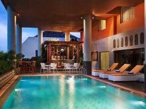 a swimming pool in a building with chairs and a table at The Royal Surakarta Heritage - Handwritten Collection in Solo