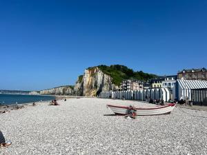 a boat sitting on a rocky beach next to the water at La Gruchette in Gruchet-Saint-Siméon
