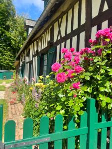 a green fence next to a house with pink roses at La Gruchette in Gruchet-Saint-Siméon +18 photos