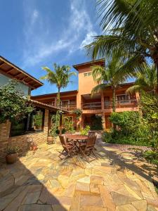 a patio with a table and chairs in front of a house at Pousada Tempo Rei in Boicucanga
