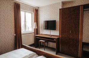 a hotel room with a bed and a desk with a television at Hotel & Restaurant Krone in Märkt in Weil am Rhein