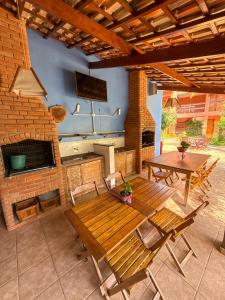 a patio with a wooden table and chairs and a kitchen at Pousada Tempo Rei in Boicucanga