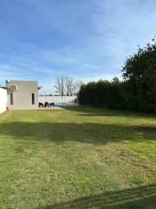 a large grassy yard with a white house in the background at Quinta Las Lilas in Chivilcoy