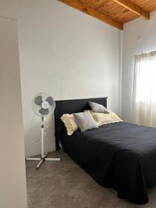 a bedroom with a black bed and a fan at Quinta Las Lilas in Chivilcoy