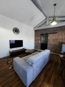 a living room with a blue couch and a brick wall at La Grange de Lilou in Aiffres