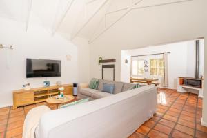 a living room with a couch and a tv at Benguela Cottage in Langebaan
