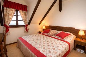 a bedroom with a bed with red pillows and a window at Rooms Bolfan Vinski Vrh in Hrašćina