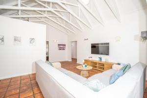 a living room with white furniture and a flat screen tv at Benguela Cottage in Langebaan