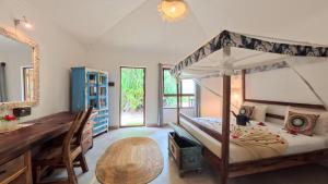 a bedroom with a large canopy bed and a desk at Paje By Night Bungalows in Paje +103 photos