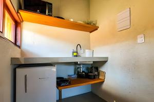 a small kitchen with a counter and a refrigerator at Maysu Patacho Chalé Piscina Privativa in Pôrto de Pedras