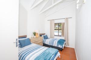 two beds in a room with a window at Benguela Cottage in Langebaan