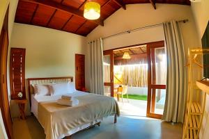 a bedroom with a bed and a sliding glass door at Maysu Patacho Chalé Piscina Privativa in Pôrto de Pedras