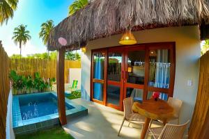 a villa with a pool and a table and chairs at Maysu Patacho Chalé Piscina Privativa in Pôrto de Pedras
