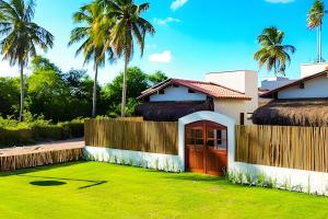 a house with a lawn in front of it at Maysu Patacho Chalé Piscina Privativa in Pôrto de Pedras