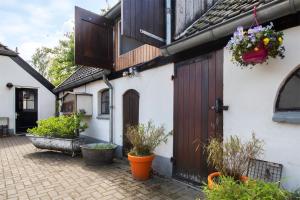a white house with a wooden door and some plants at Bed and Breakfast Lovenem - ruime studio met zwembad en sauna op de Veluwe in Leuvenheim