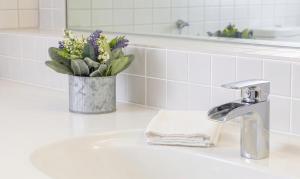a bathroom sink with a faucet and a vase of flowers at Hotel & Restaurant Krone in Märkt in Weil am Rhein +16 photos