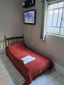 a bedroom with a bed with a red blanket and a window at Básico e funcional, com 2 ambientes, sem fogão, com garagem, zona nobre in Pelotas