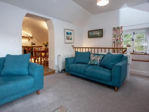 a living room with two blue couches and a kitchen at Tuckenhay, 4 Castle Cottage- Fcn in Ashsprington