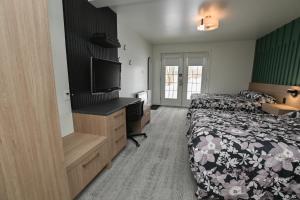 a hotel room with a bed and a flat screen tv at Motel Blanche d'Haberville in Saint-Jean-Port-Joli